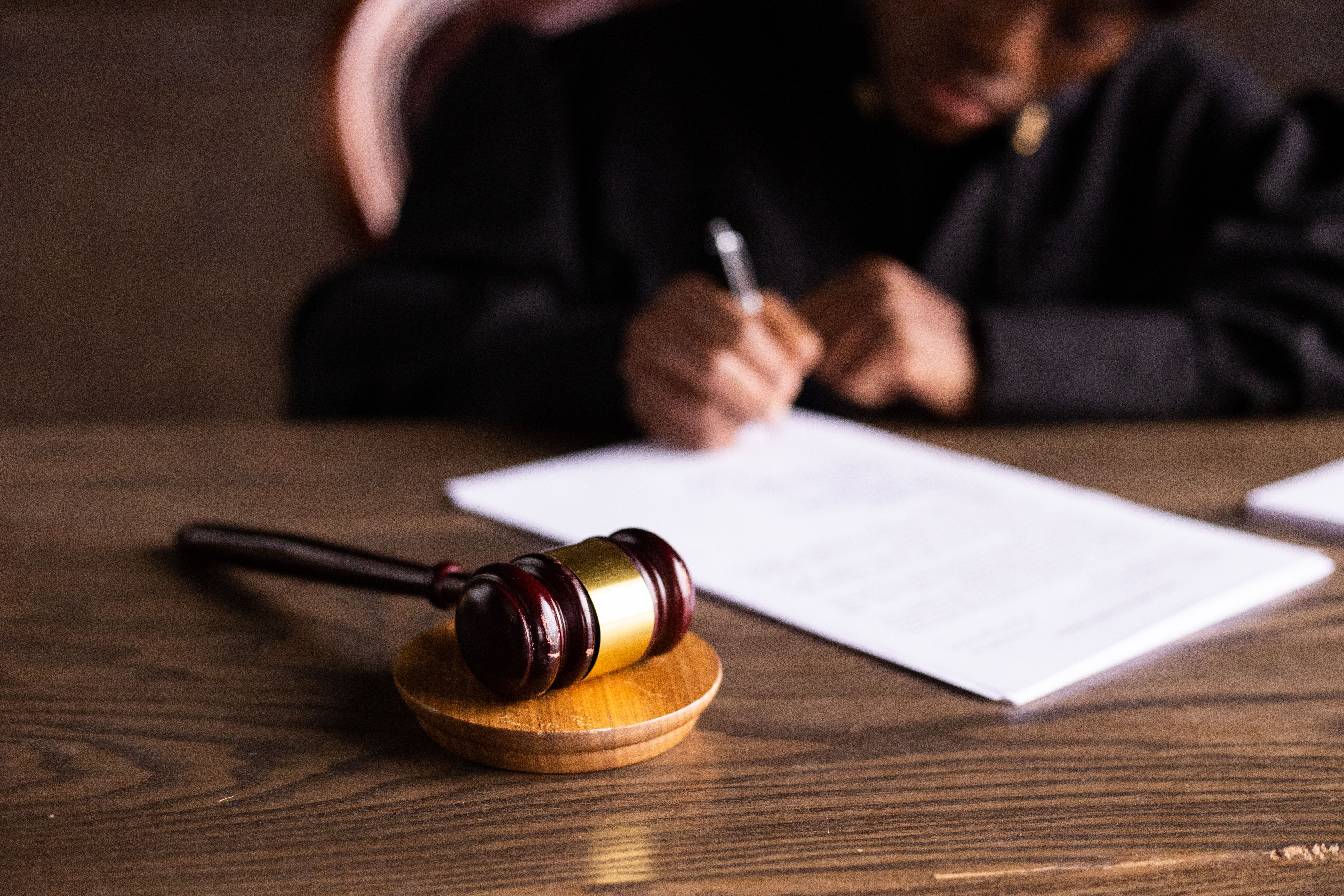Judge signing documents beside a gavel in a courtroom