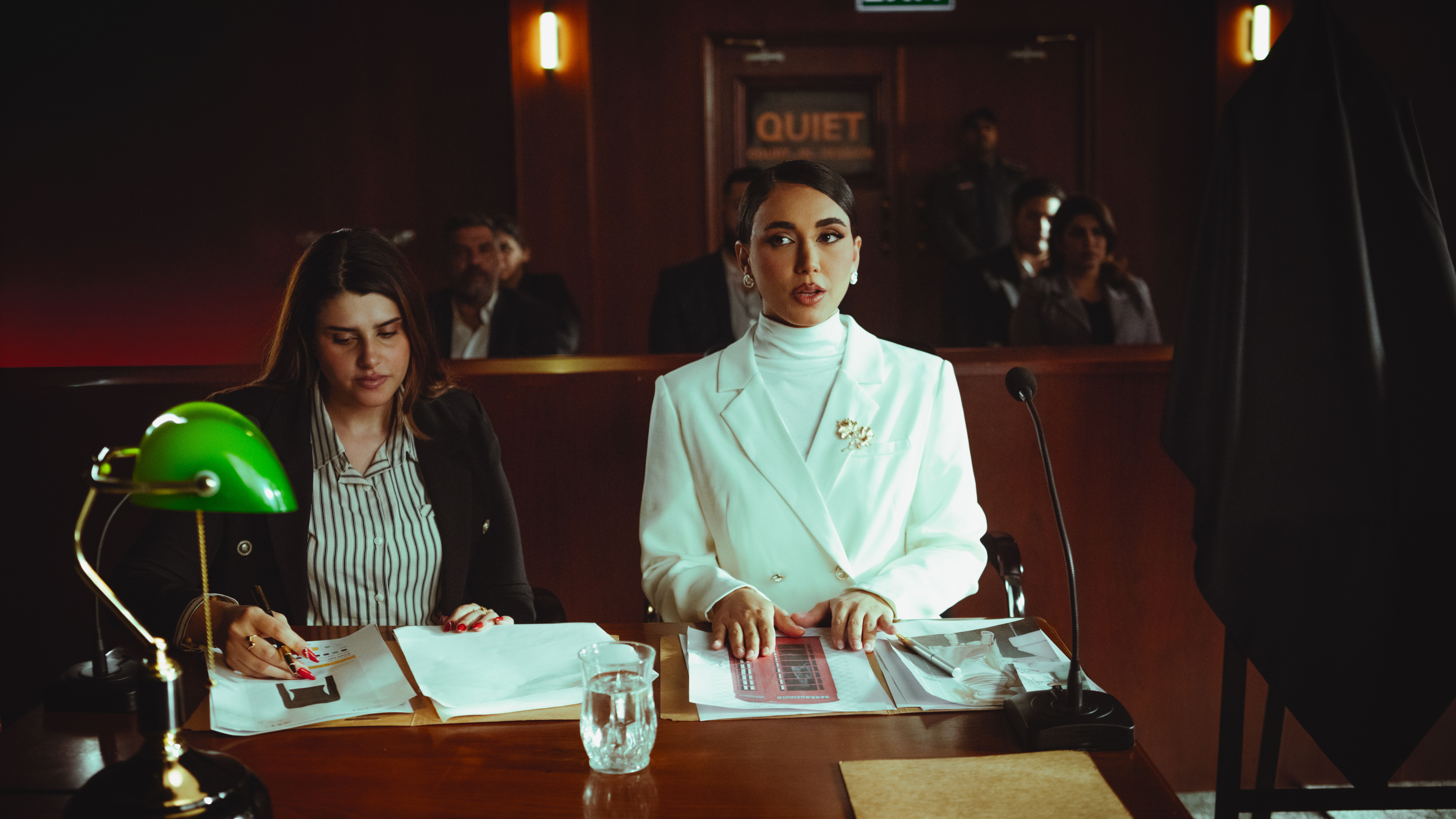 Two female lawyers in a courtroom reviewing legal documents and preparing their case