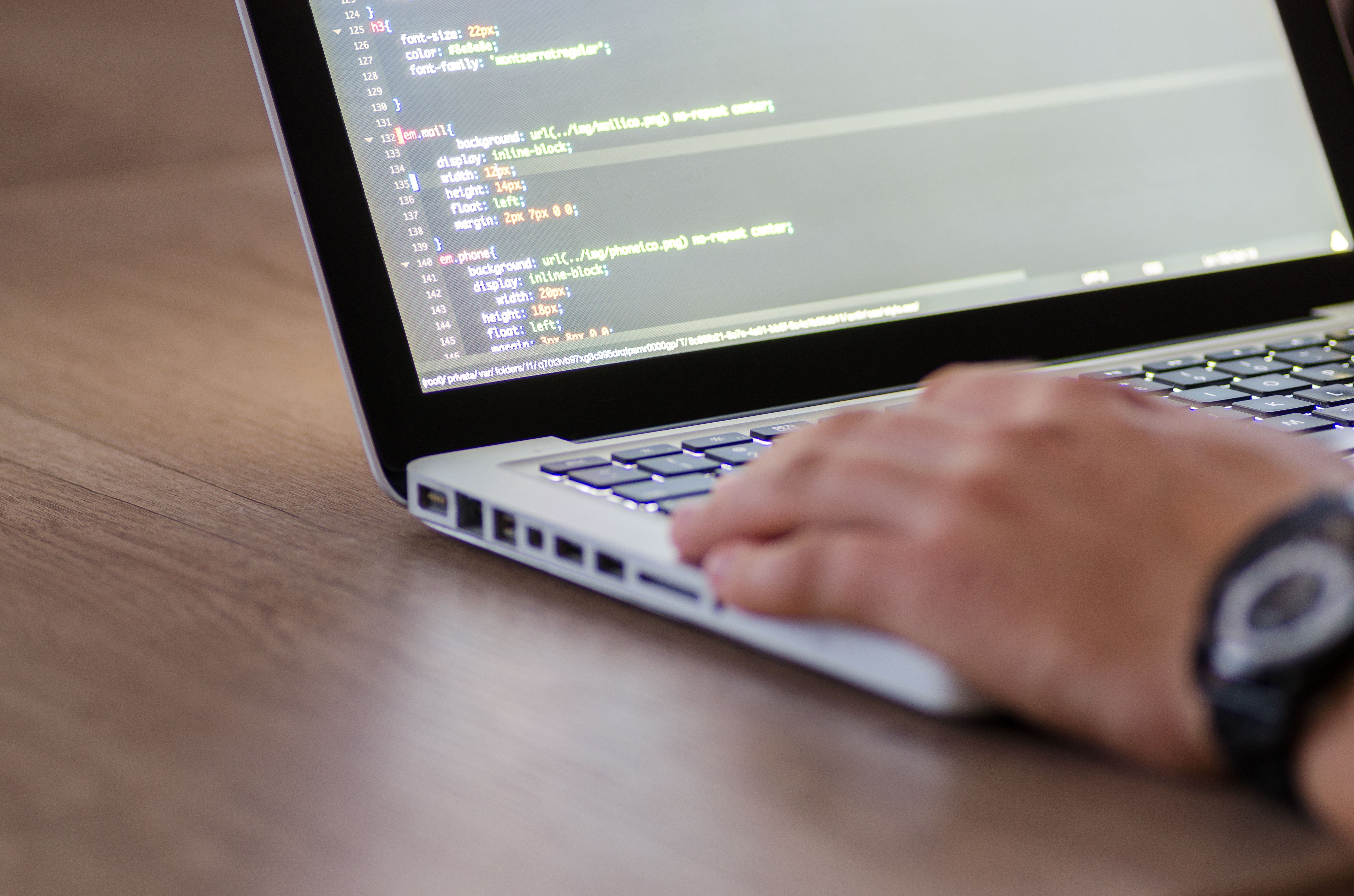 Developer coding HTML on a laptop while optimizing a WordPress website