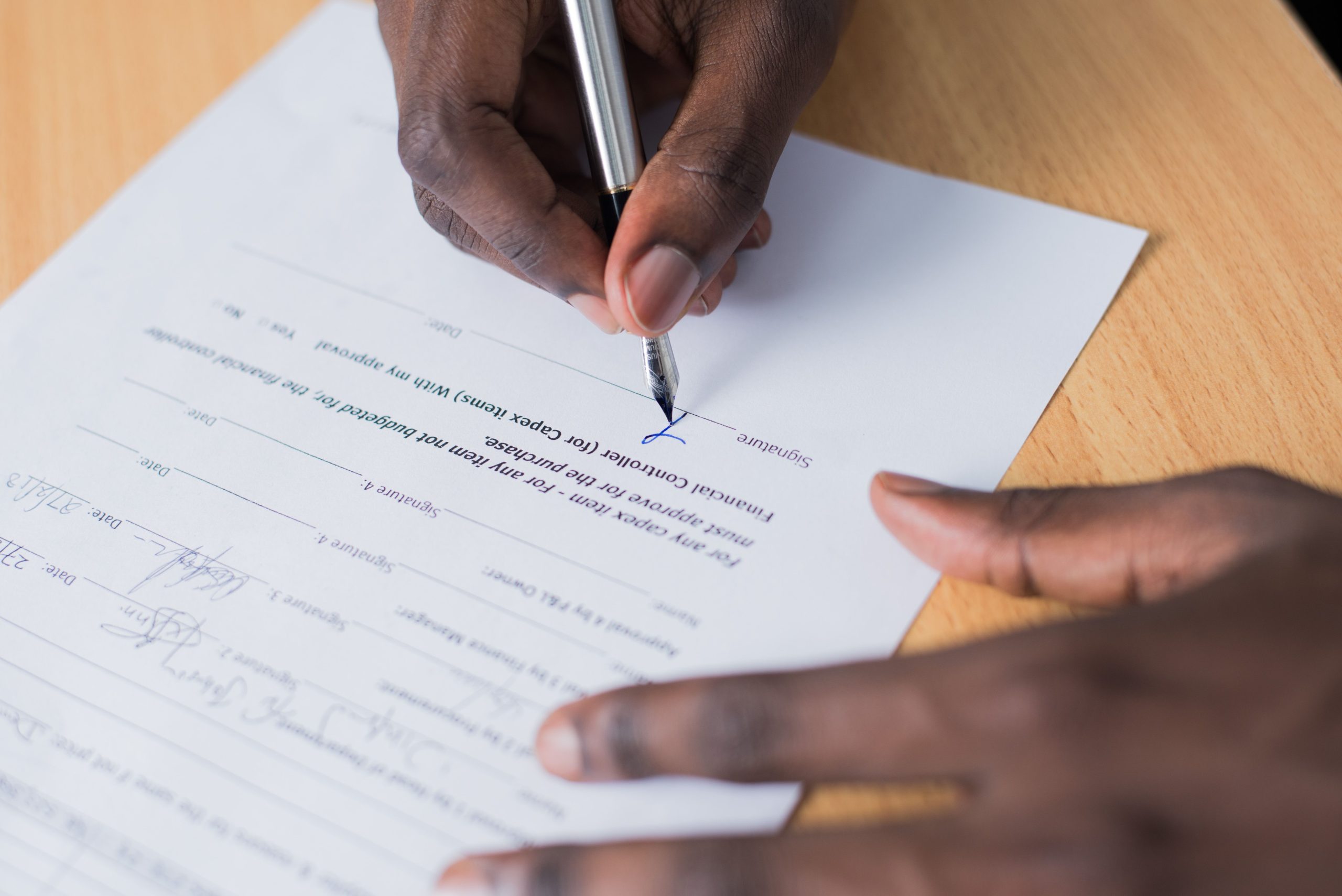 Hand signing a business contract, illustrating the agreements involved in music licensing.