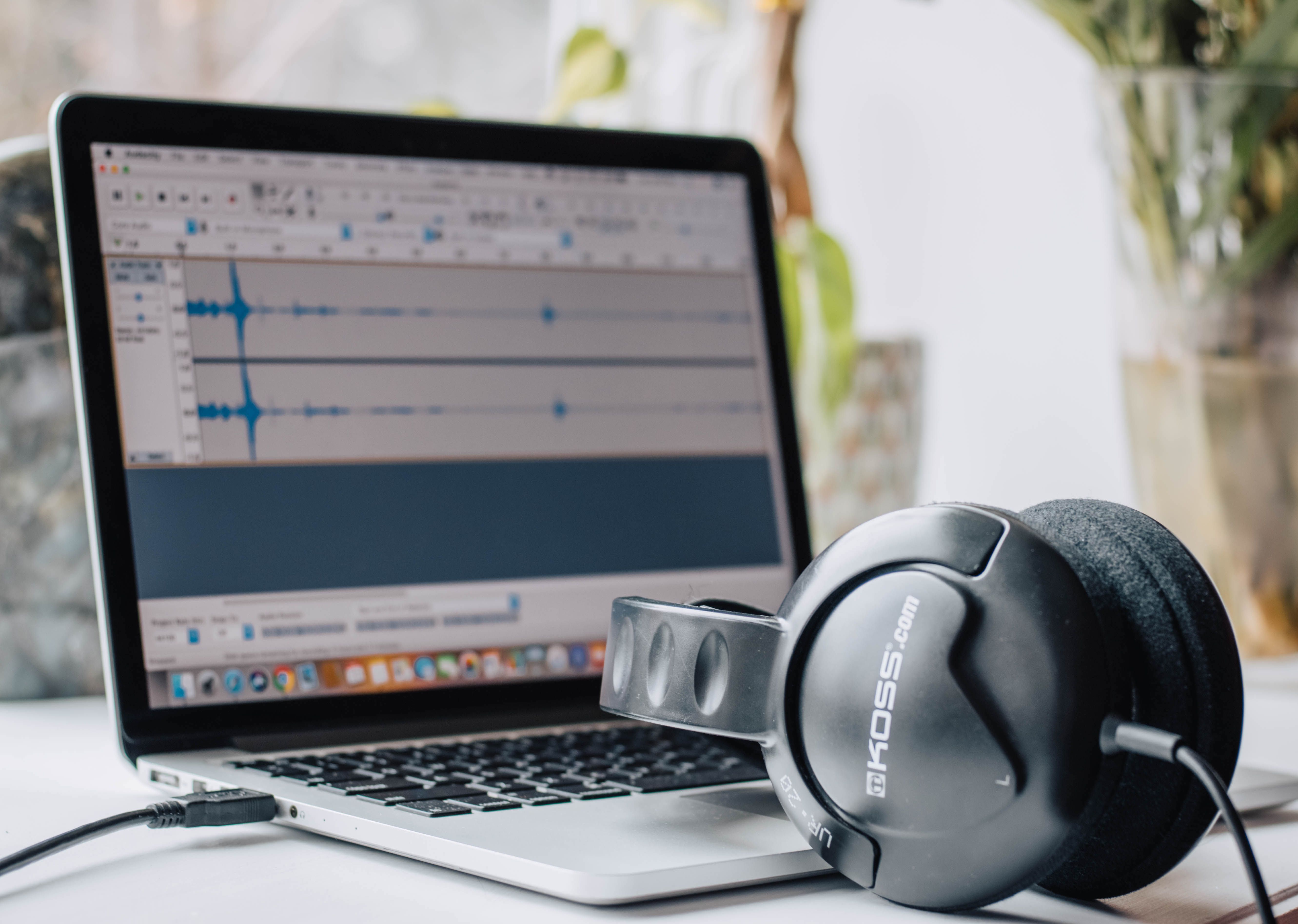 Laptop displaying audio-editing software beside headphones, representing digital music production and rights management.